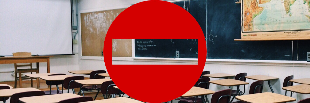 Un'aula scolastica completamente vuota. Sovrapposto, un cartello di divieto d'accesso