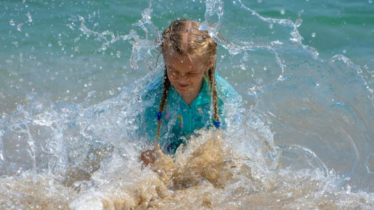Bambina che gioca vestita dentro nel mare. La libertà di sporcarsi dovrebbe essere citata come diritto fondamentale